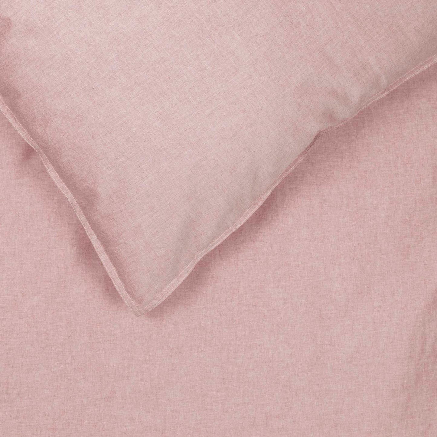 Detail van een omgeslagen hoek van dekbedovertrek Bo in de kleur peach. Een roze/oranje uni dekbedovertrek van chambray met rondom een stoer dubbel stiksel.