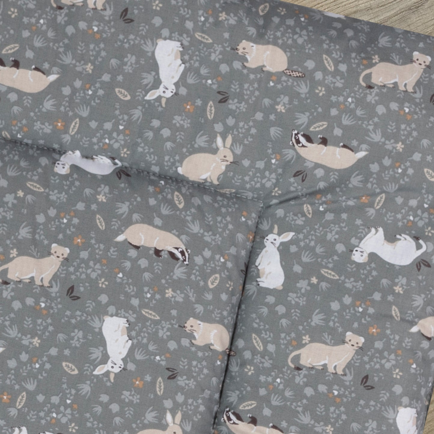Detail van boxkleed Bunny met een donker grijze ondergrond met lichtgrijze bloemetjes en vrolijke konijnen, dassen en hermelijnen.