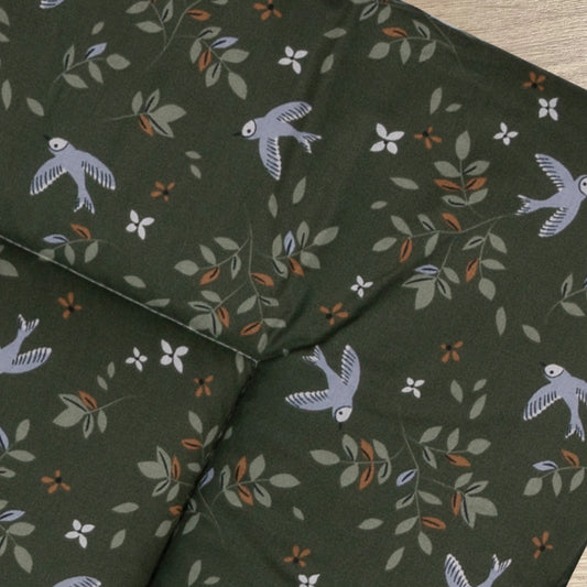 Detail van boxkleed Merel met een mooie print van bloemen en vogels in lila, licht groen en camel op een donkergroene ondergrond.