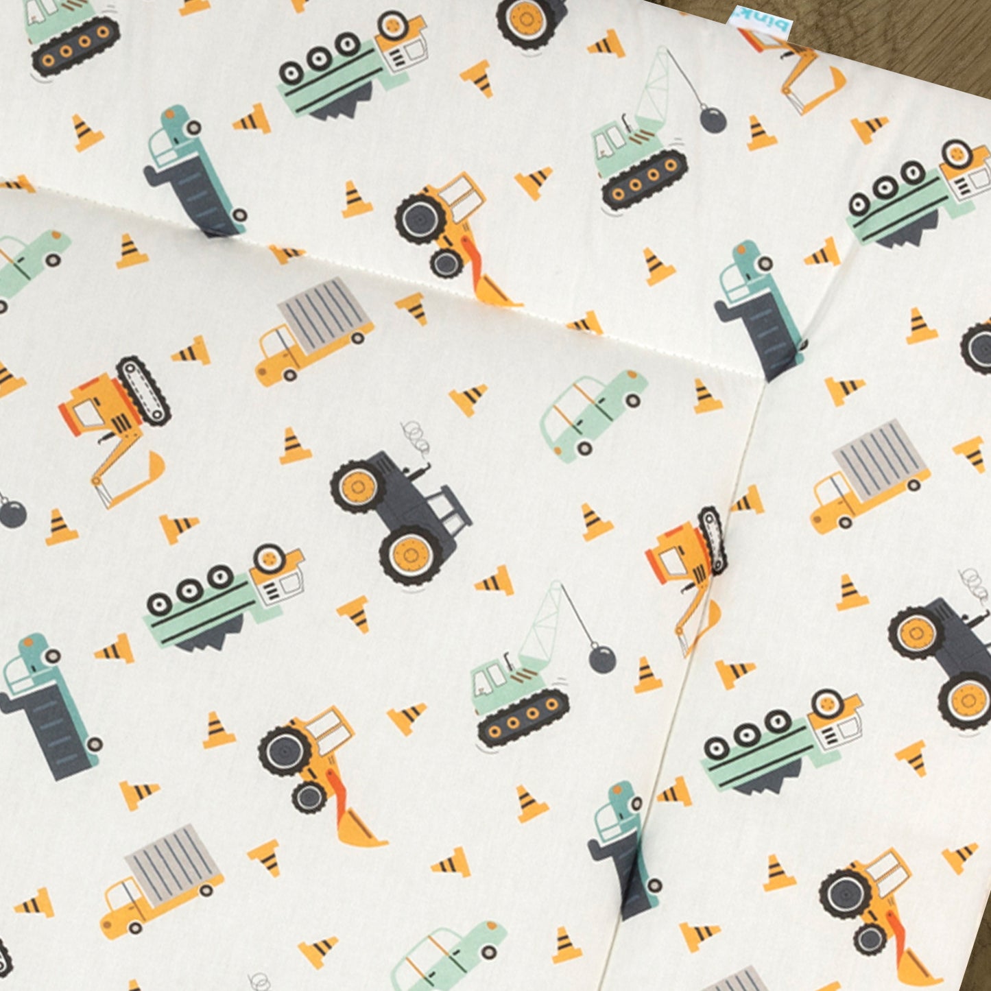 Detail van boxkleed Bram met een heeft een leuke voertuigen print in de kleuren licht grijs, donkergrijs, oranje, geel en mintgroen op een ecru ondergrond.