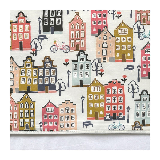 Laken Adam heeft een vrolijke print met grachten huisjes in mooie tinten zoals peach, roze, bleu, grijs en mosterdgeel op een ecru ondergrond.